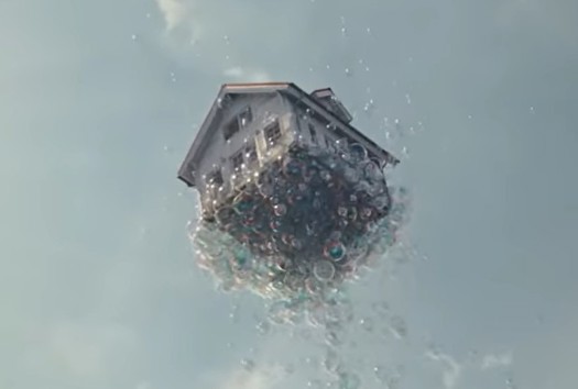 Ein Haus wird von vielen Seifenblasen in den Himmel gehoben.