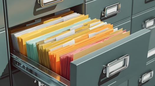 geöffnete Aktenschrankschublade mit mehrfarbigen Akten und Ordnern in einer Büroumgebung
